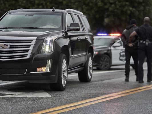 Man being arrested by cop in front of cadillac