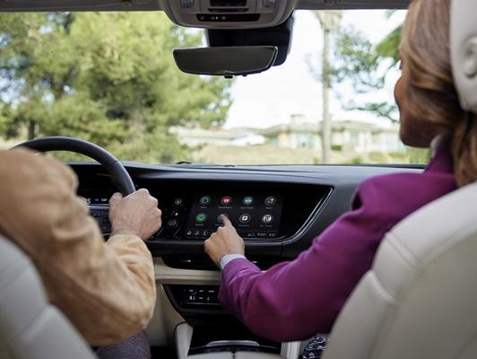 couple in car touching touch screen on buick