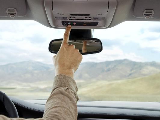 Man pushing onstar button on rear view mirror