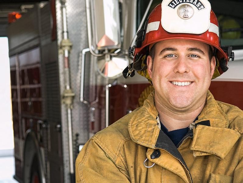 Fireman with a red hat in a firestation smiling