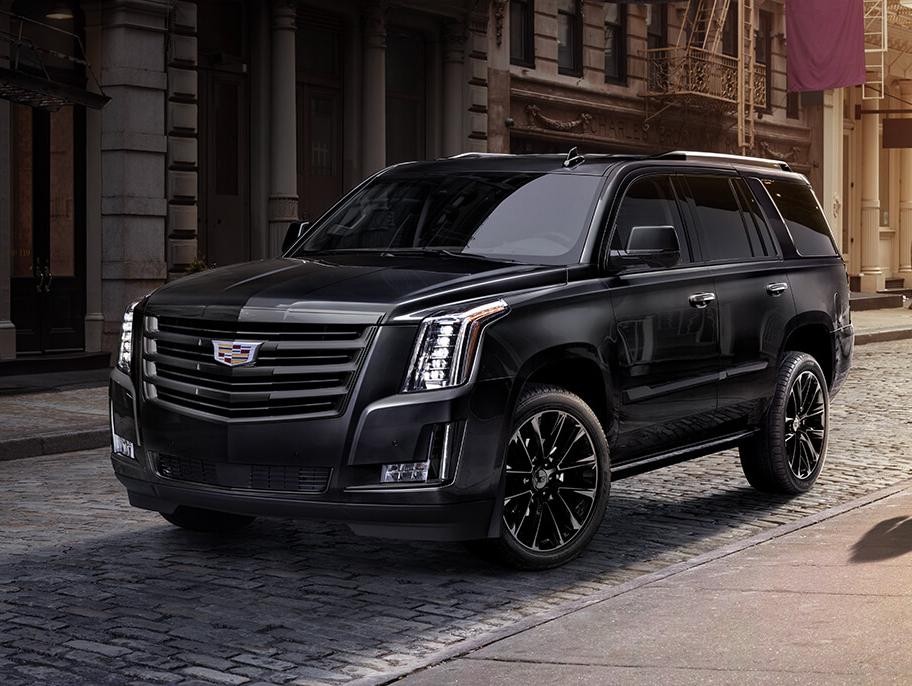 A Cadillac Escalade driving along a cobblestone street.