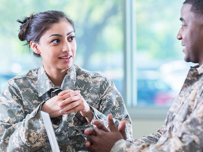 A military woman discussing options with man on laptop