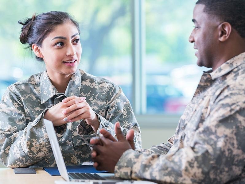 A military woman discussing options with man on laptop