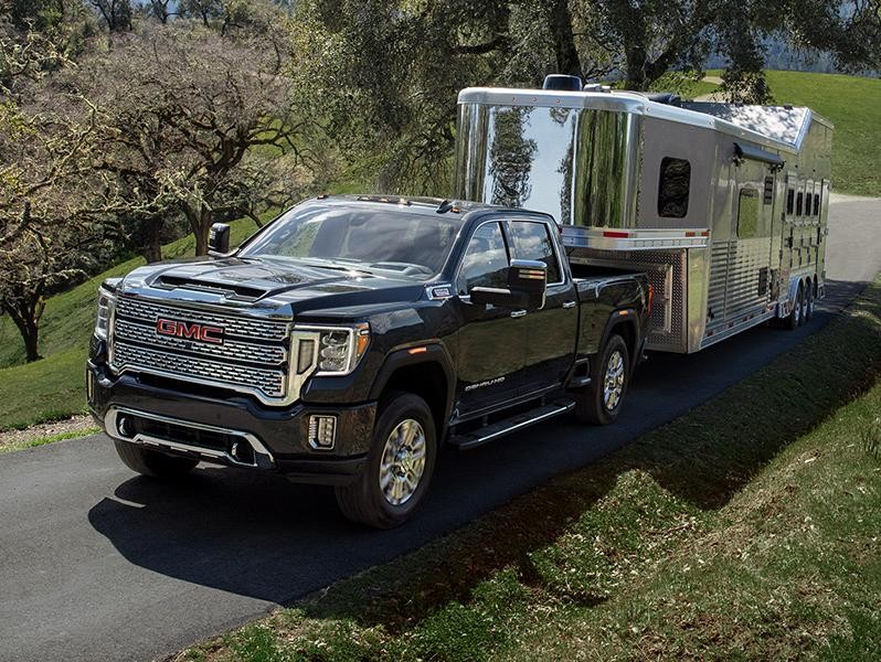 Un negro GMC Sierra 2500HD remolcando un remolque de caballos cuesta arriba.