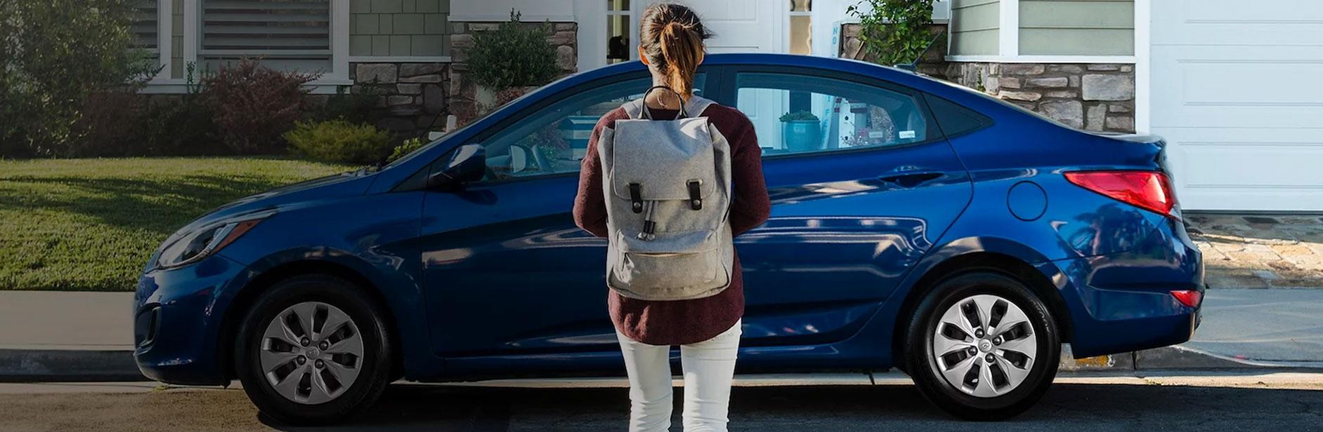 Collage Grad Program - Young adult wearing a backpack standing next to a Hyundai