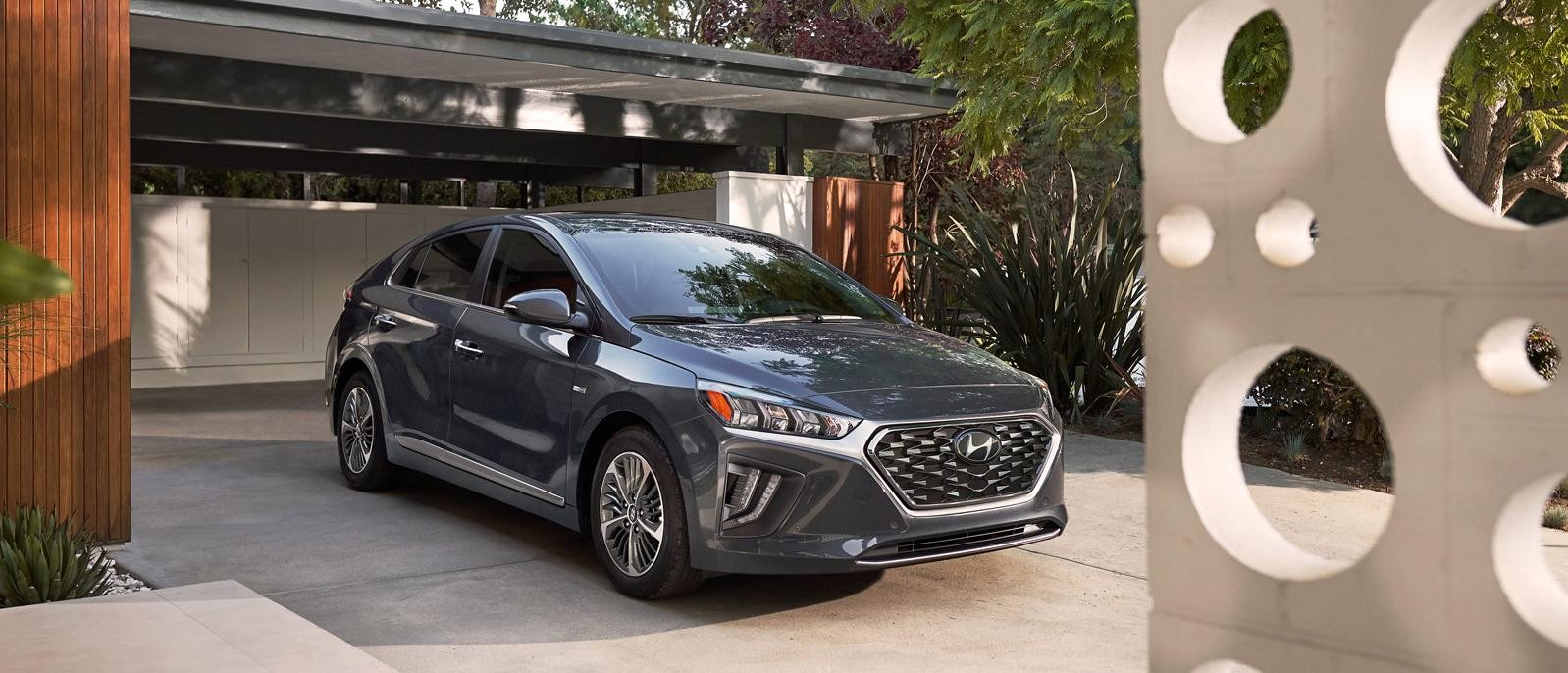 A grey Hyundai Ioniq Plug-In Hybrid parked in the driveway of a modern home.