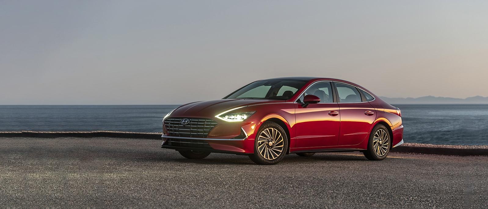 Red Sonata hybrid parked near an ocean.