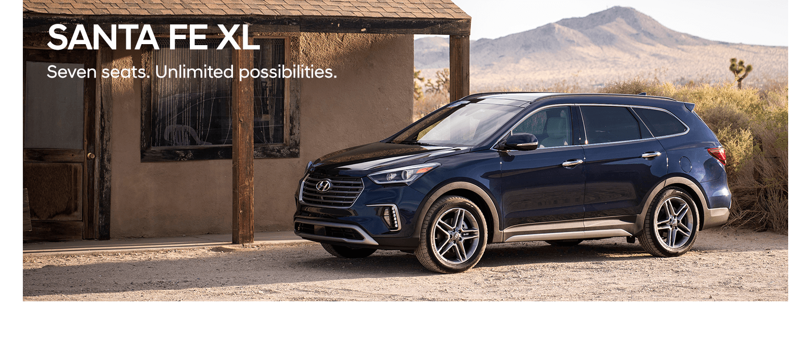 An blue Hyundai Santa Fe XL parked by a desert store.