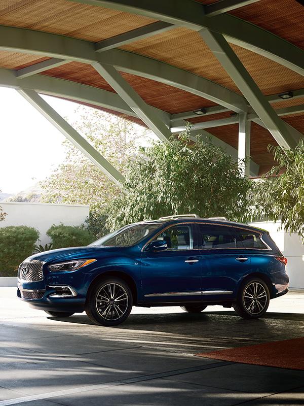 Profile view of a blue INFINITI QX60 parked under an archway. Profile view of a blue INFINITI QX60 parked under an archway.