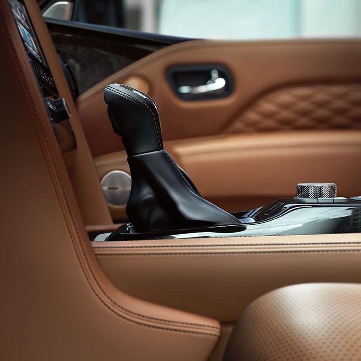 Interior detail view of an INFINITI QX80 shift handle and leather accents. Interior detail view of an INFINITI QX80 shift handle and leather accents.