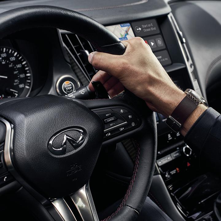 Close-up view of driver using the paddle shifter of an INFINITI Q50. Close-up view of driver using the paddle shifter of an INFINITI Q50.