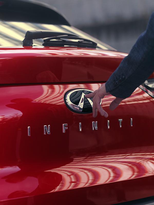 Rear view of a man at the trunk of a red INFINITI QX55. Rear view of a man at the trunk of a red INFINITI QX55.