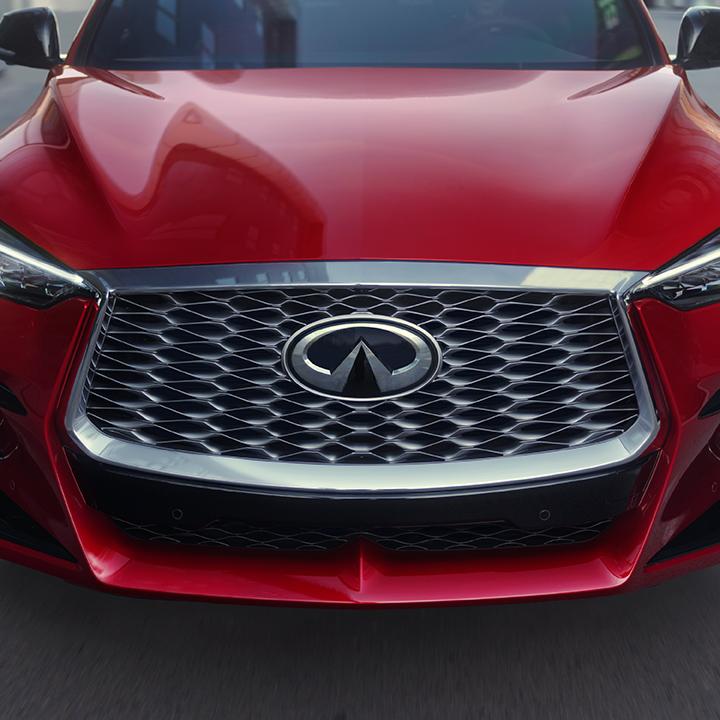 Head-on view of a red INFINITI QX55 front grille and hood. Head-on view of a red INFINITI QX55 front grille and hood.