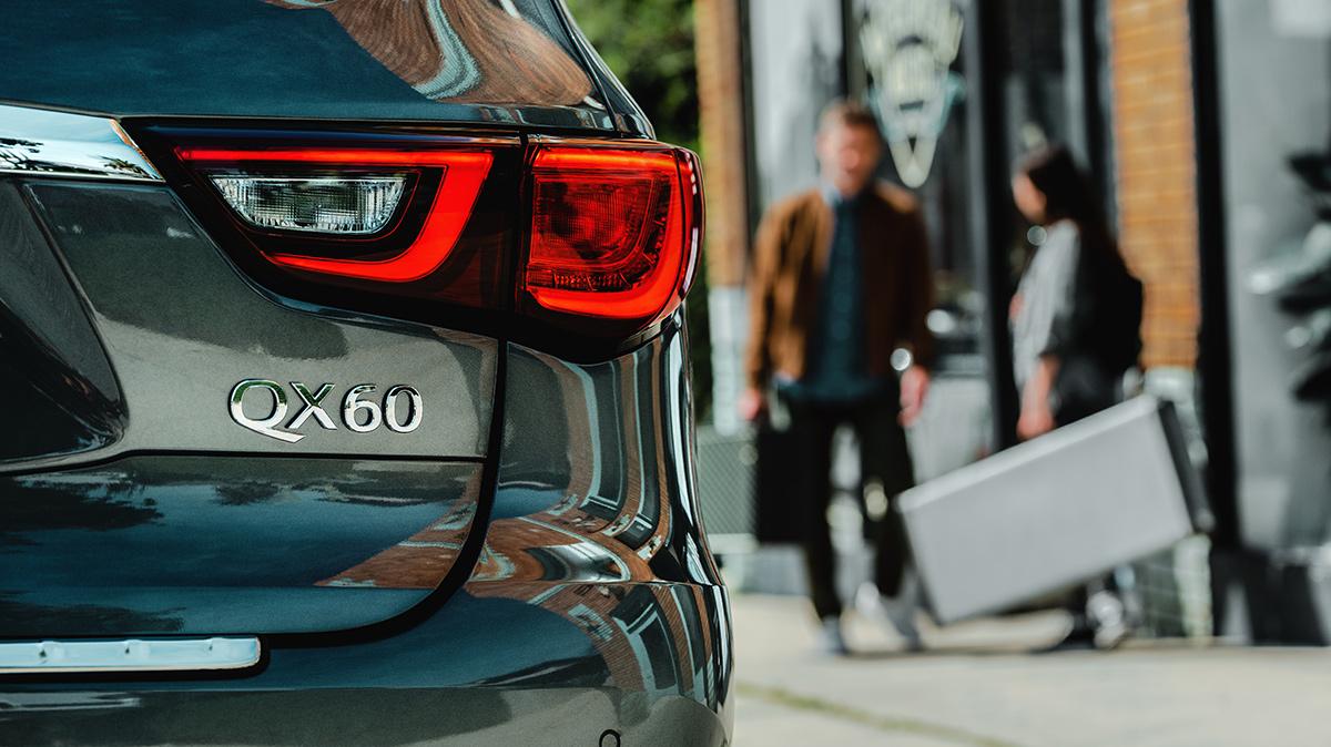 Detail of an INFINITI QX60 taillight with two pedestrians in the background. Detail of an INFINITI QX60 taillight with two pedestrians in the background.