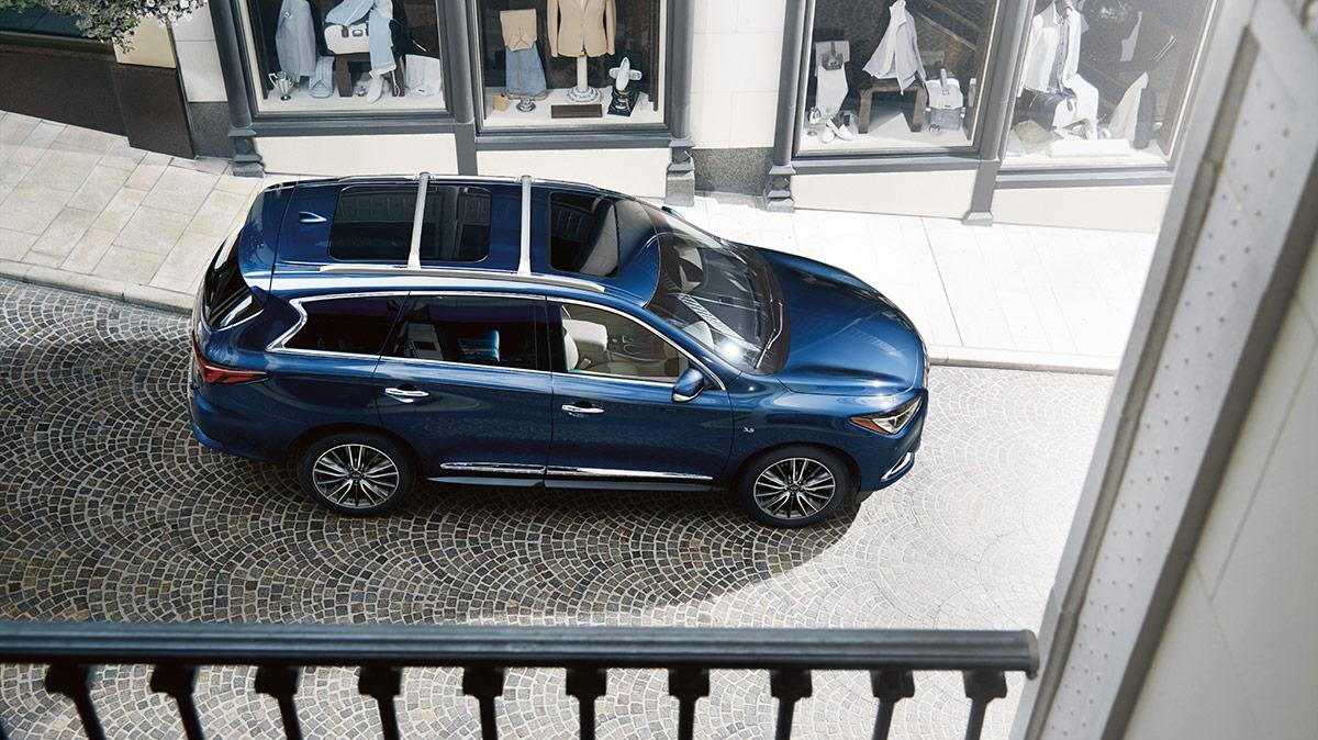 High angle view of a blue INFINITI QX60 on the street below a balcony. High angle view of a blue INFINITI QX60 on the street below a balcony.