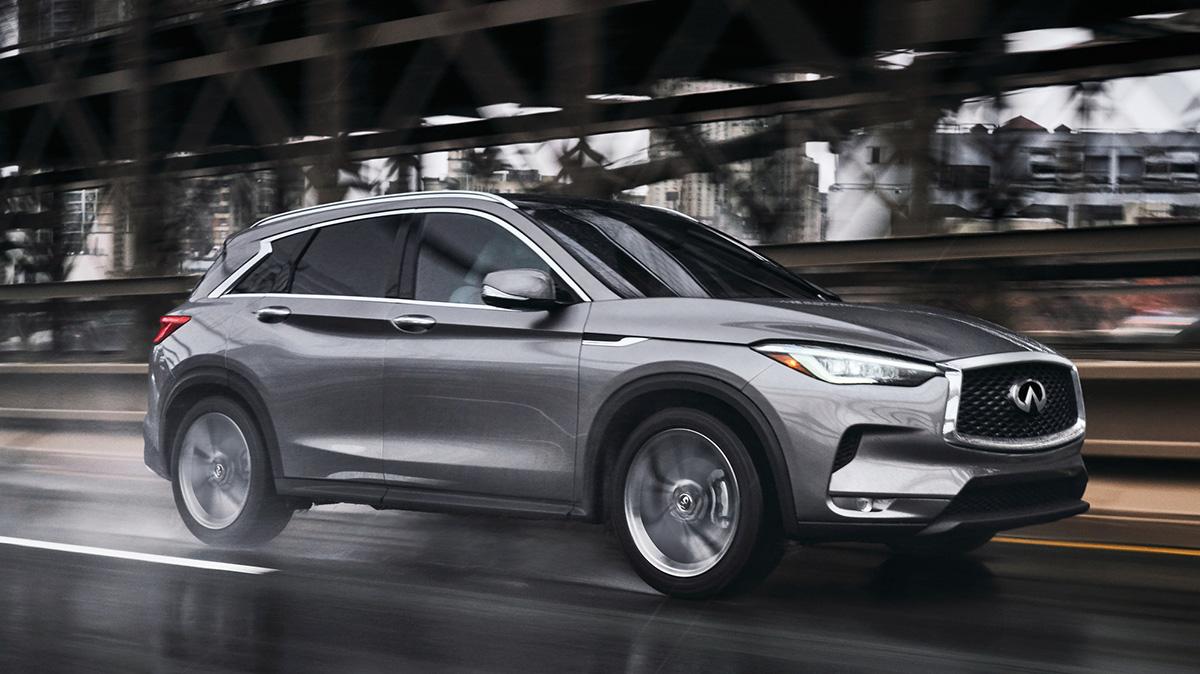 A grey INFINITI QX50 driving on a wet city street. A grey INFINITI QX50 driving on a wet city street.