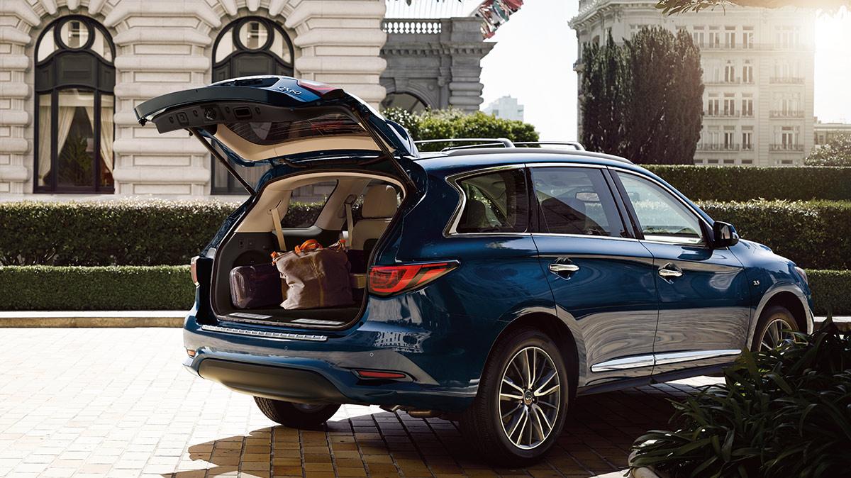 A blue INFINITI QX60 parked outside a hotel with the rear hatch open. A blue INFINITI QX60 parked outside a hotel with the rear hatch open.