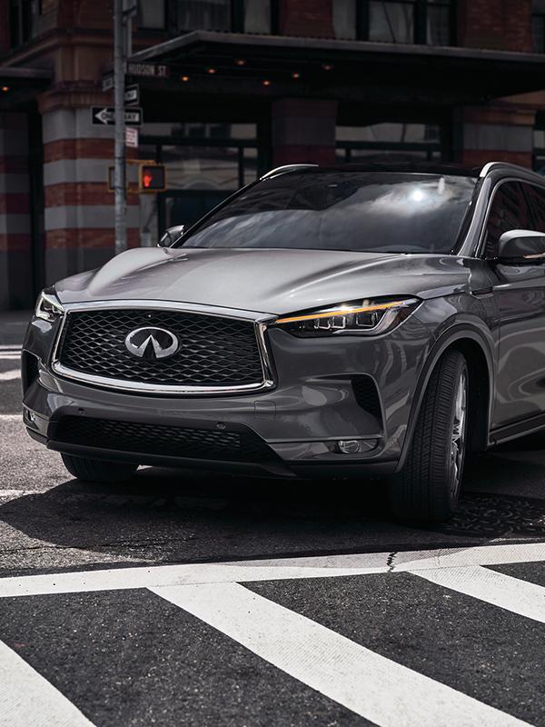 A grey INFINITI QX50 taking a corner in the city. A grey INFINITI QX50 taking a corner in the city.