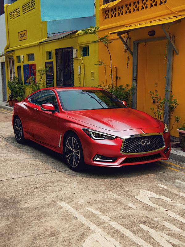 A red INFINITI Q60 parked on a side street with colorful buildings. A red INFINITI Q60 parked on a side street with colorful buildings.