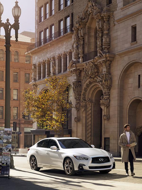 A white INFINITI Q50 parked on a city street. A white INFINITI Q50 parked on a city street.
