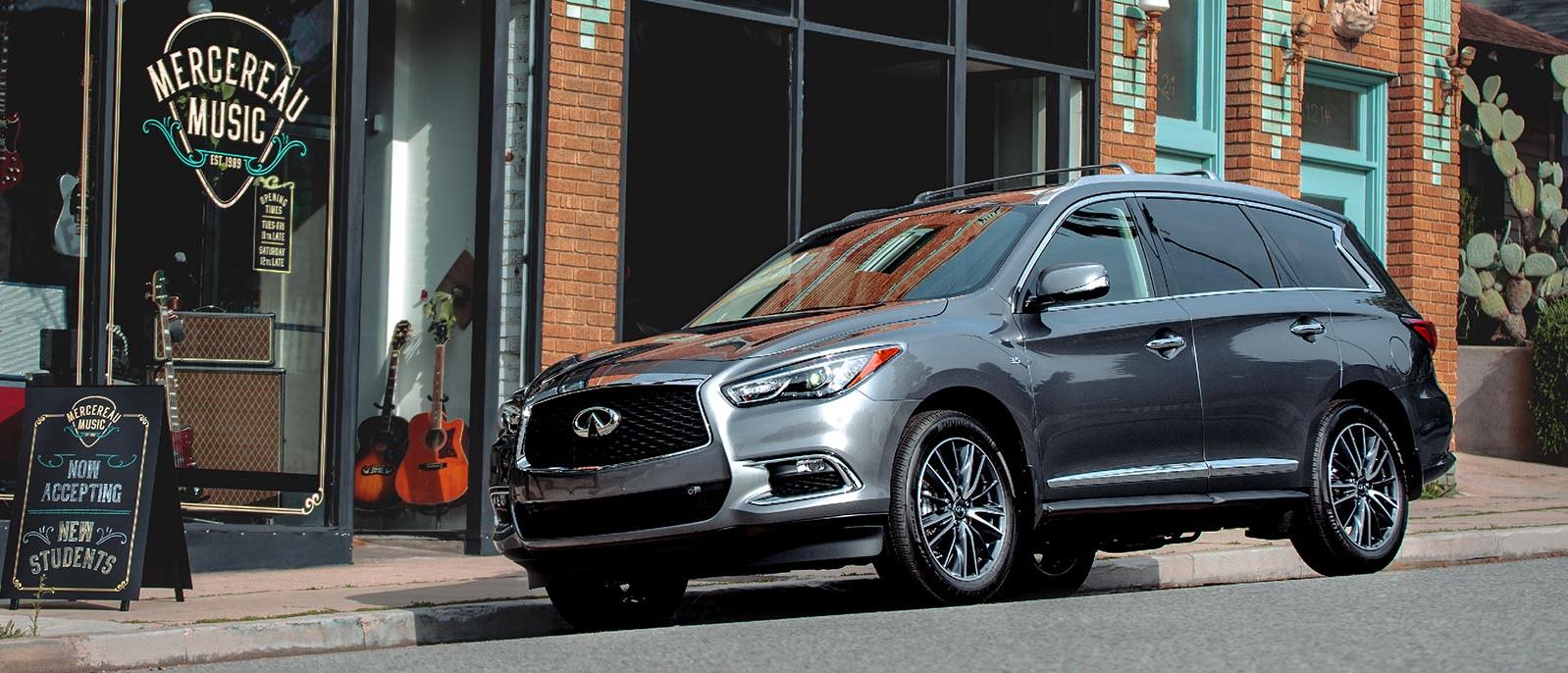 A silver INFINITI QX60 parked on the street next to a music shop. A silver INFINITI QX60 parked on the street next to a music shop.
