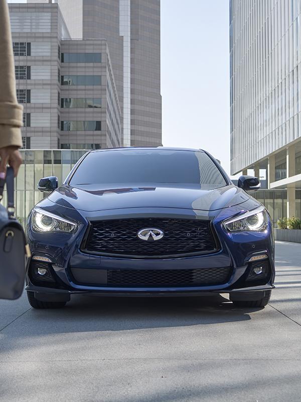 Head-on view of a blue INFINITI Q50 parked on a city street. Head-on view of a blue INFINITI Q50 parked on a city street.