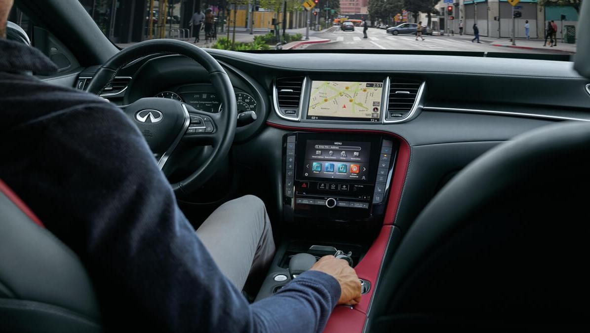 View of the front of the cabin of an INFINITI QX55 driving through a city.