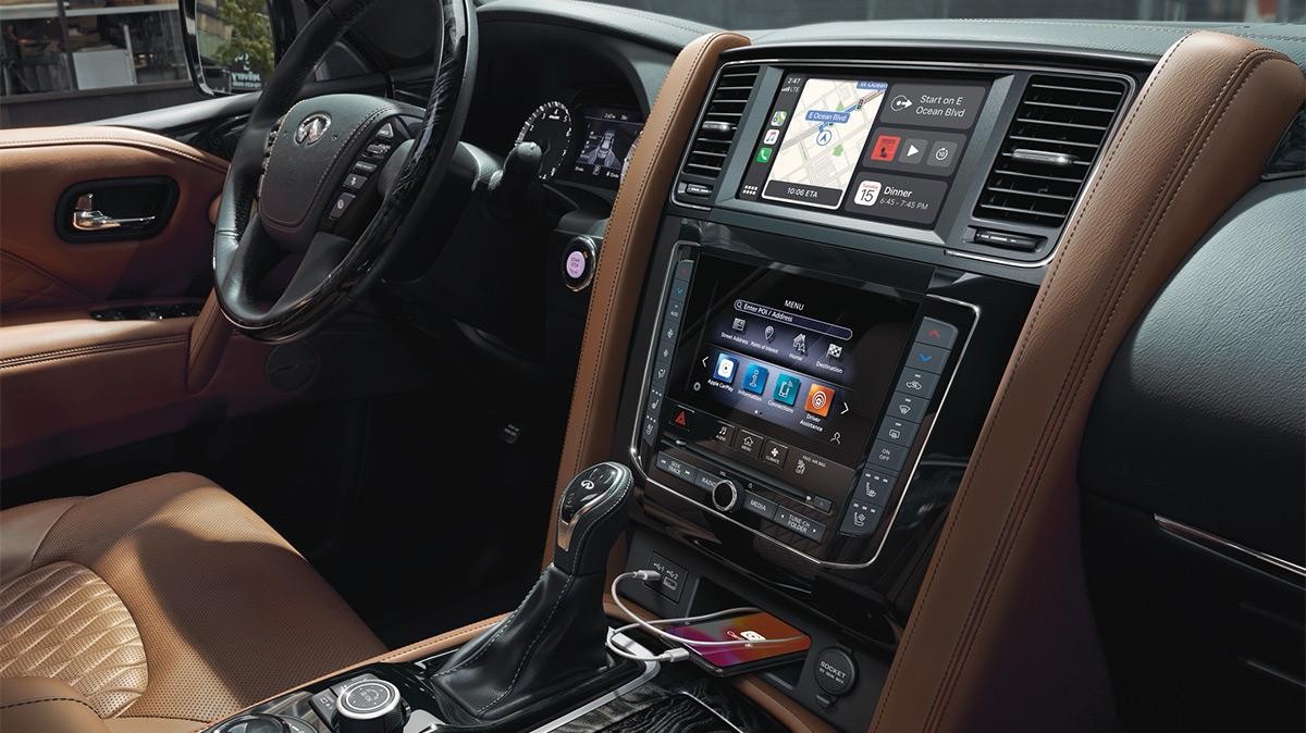 Interior view of an INFINITI QX80 front seats and dashboard, featuring Apple CarPlay.