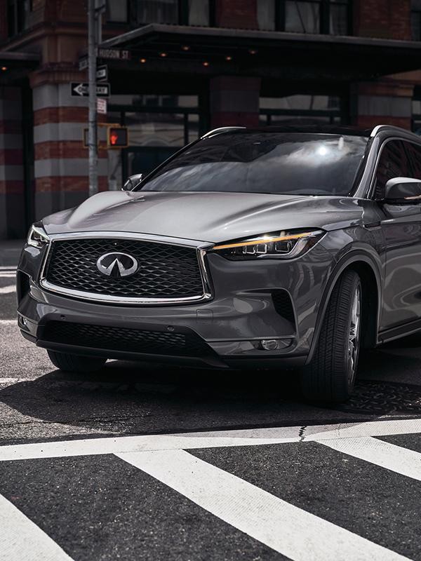 A grey INFINITI QX50 taking a corner in the city.