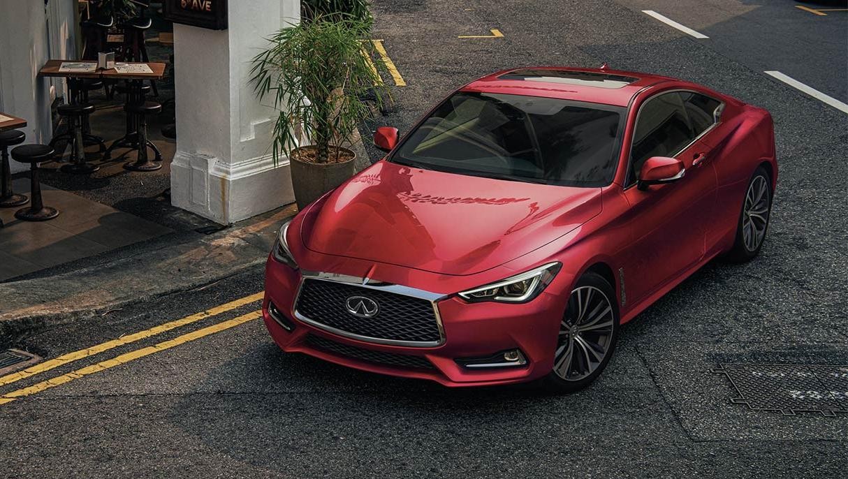 Red INFINITI Q60 parked on a street in front of a cafe