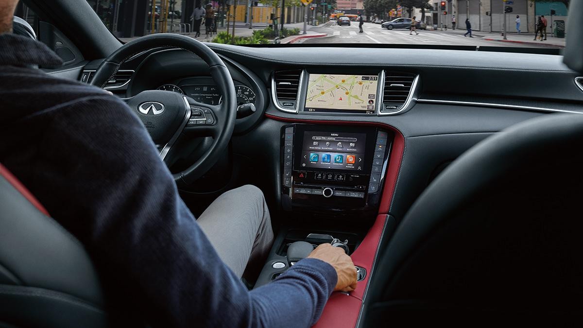 View of the front of the cabin of an INFINITI QX55 driving through a city.