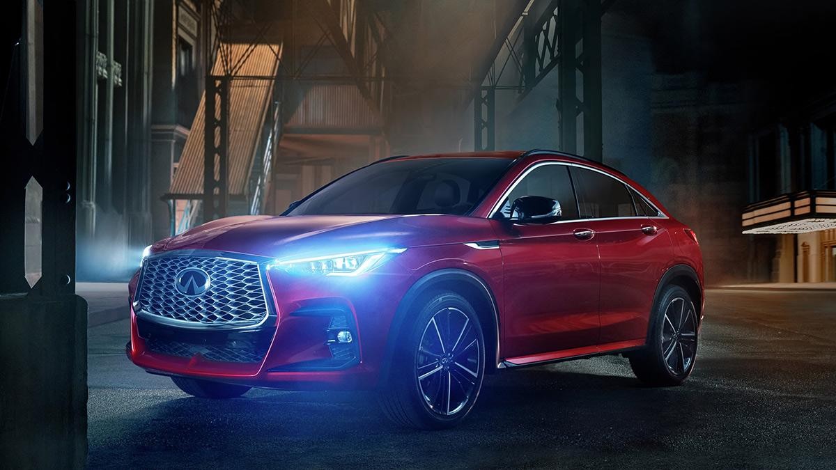 A red QX55 with its headlights on in a foggy city street.