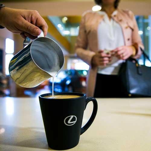 Pouring creamer into Lexus coffee cup