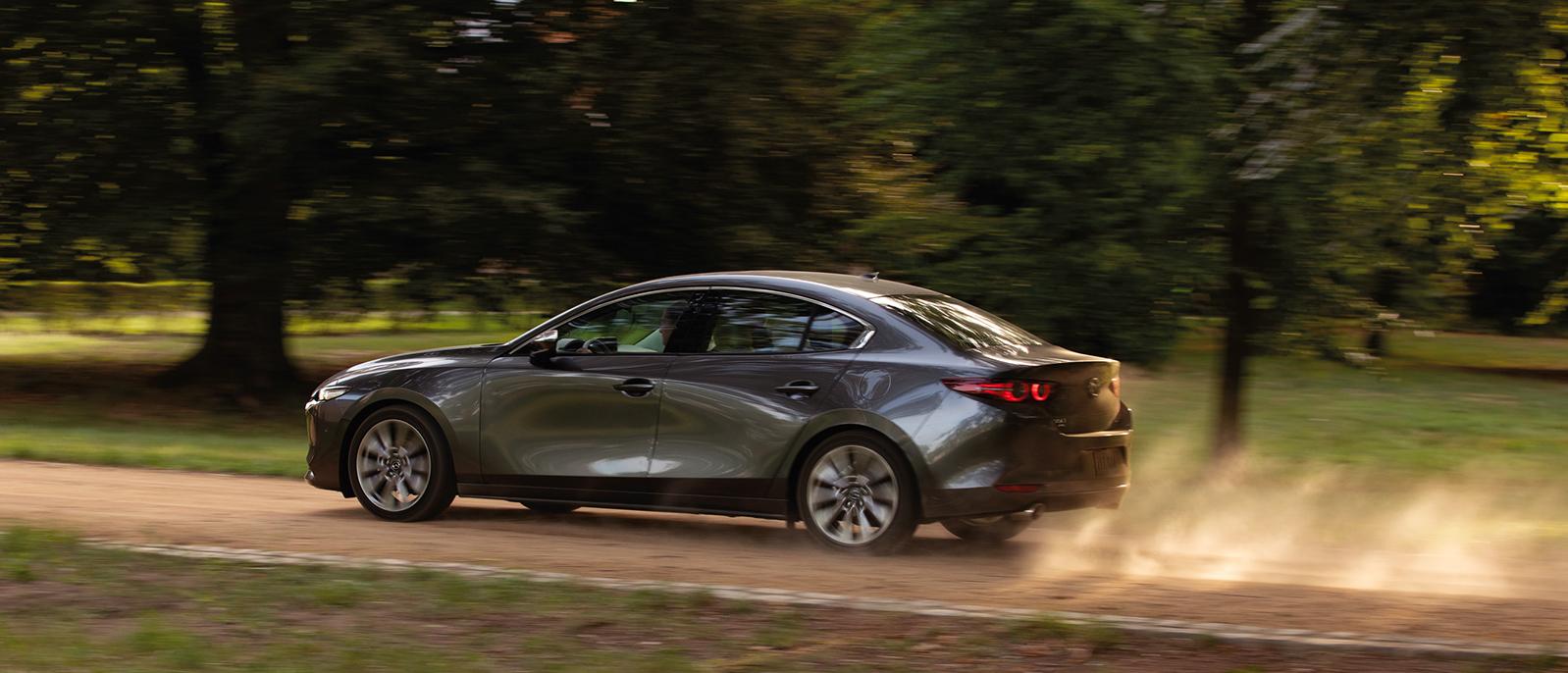 A 2020 Mazda3-Sedan driving down a dirt road. A 2020 Mazda3-Sedan driving down a dirt road.