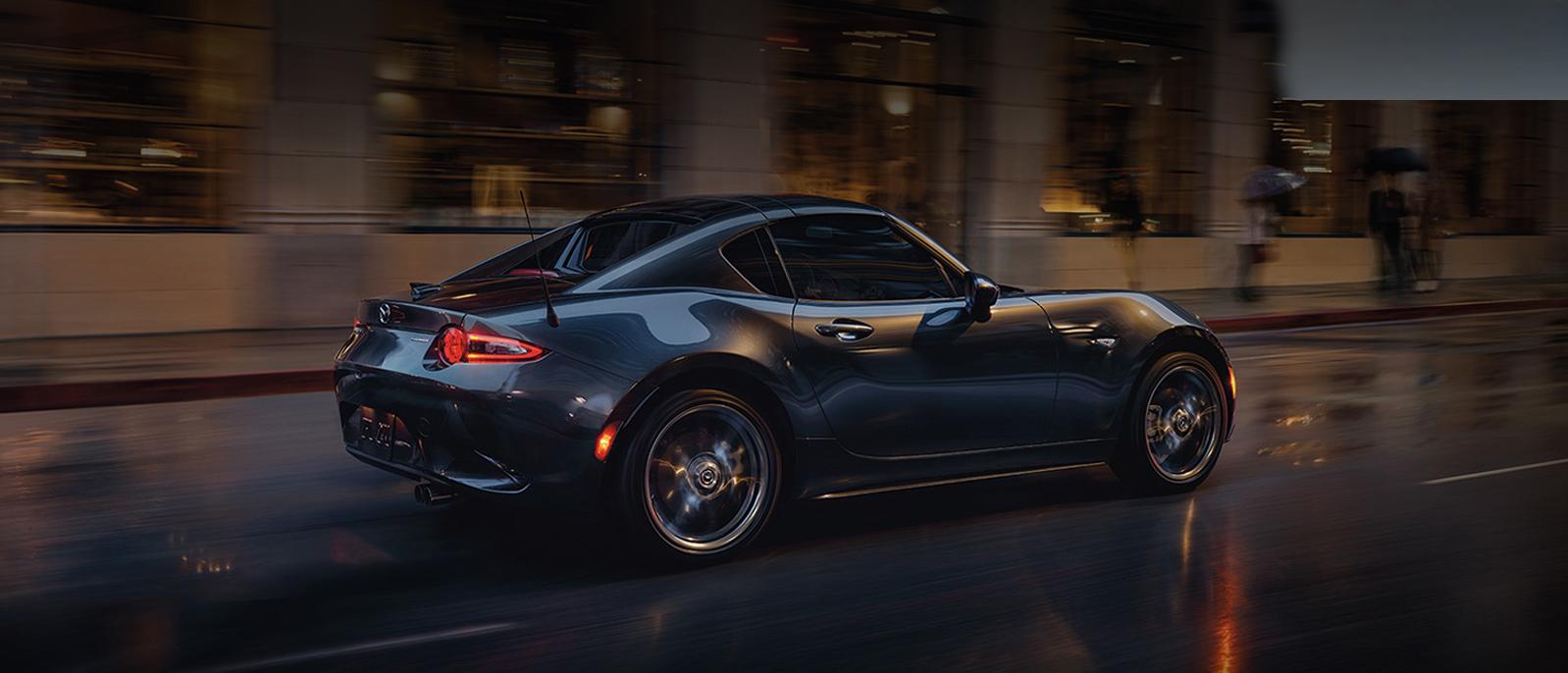 A 2022 Mazda MX 5 Miata RF driving on the road. A 2022 Mazda MX 5 Miata RF driving on the road.
