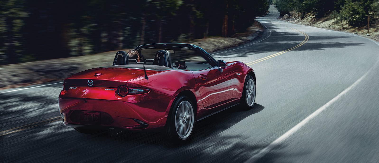 A 2020 MX-5 Miata driving along a curvy road. A 2020 MX-5 Miata driving along a curvy road.