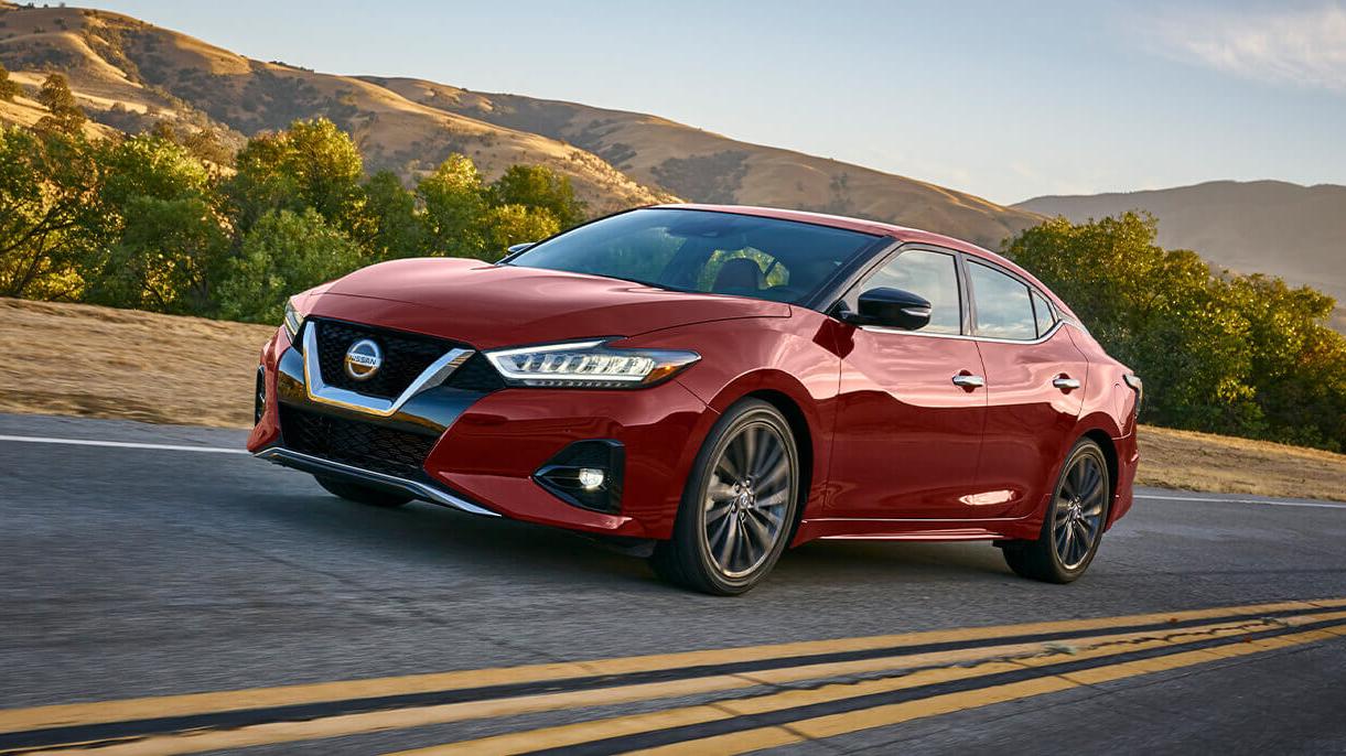 Red Nissan Rouge Driving down a road