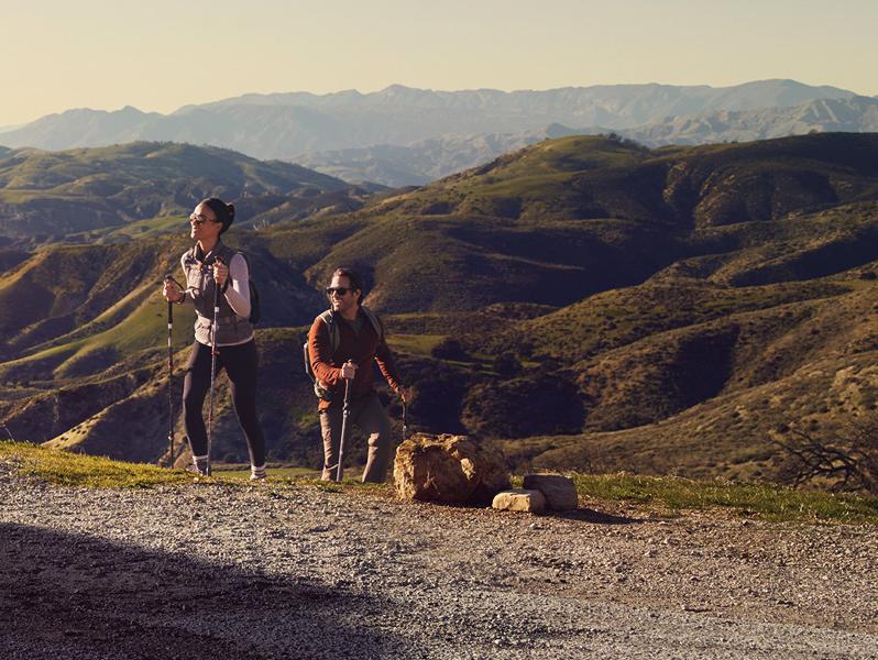 A couple coming back from a hike at a scenic overlook above a city.