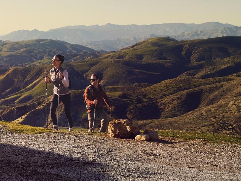 A couple coming back from a hike at a scenic overlook above a city.