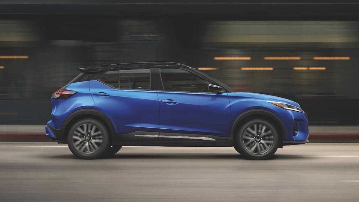 Side shot of a blue Nissan Kicks on driving on a city street