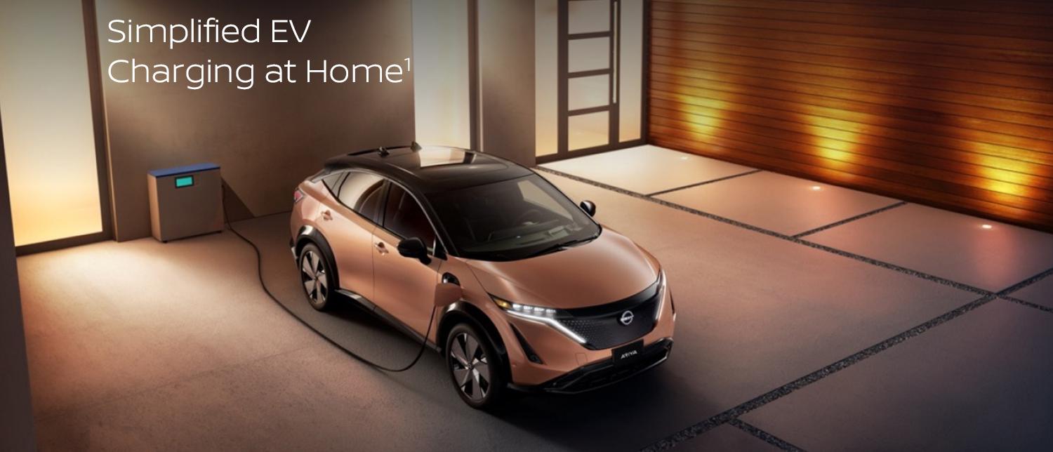 Nissan ARIYA plugged in and charging outside a home.