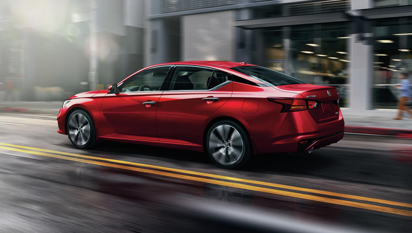 Red Nissan Altima cruising on the road.