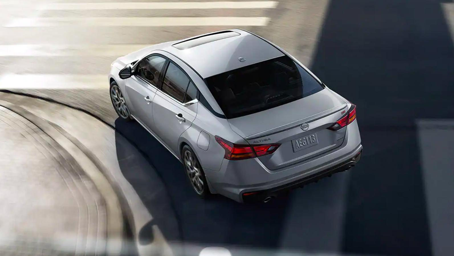 White 2023 Nissan Altima top rear view while cruising on the road. White 2023 Nissan Altima top rear view while cruising on the road.