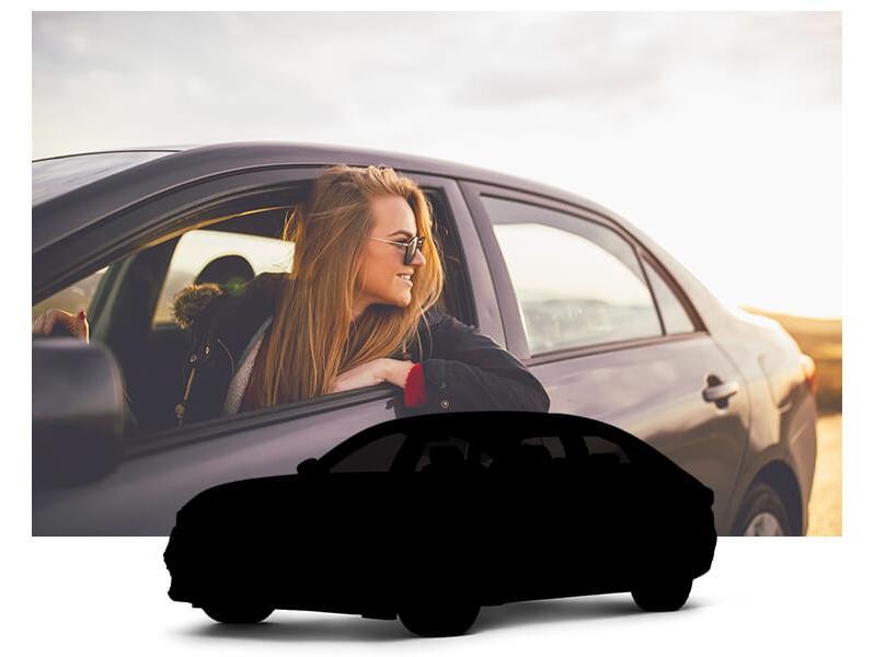 A young woman wearing sunglasses, driving a sedan