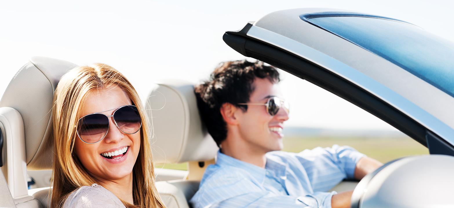 Beautiful young couple sitting in their car and enjoying in the road trip. The focus is on the woman.