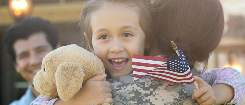 Young girl embracing her military mother