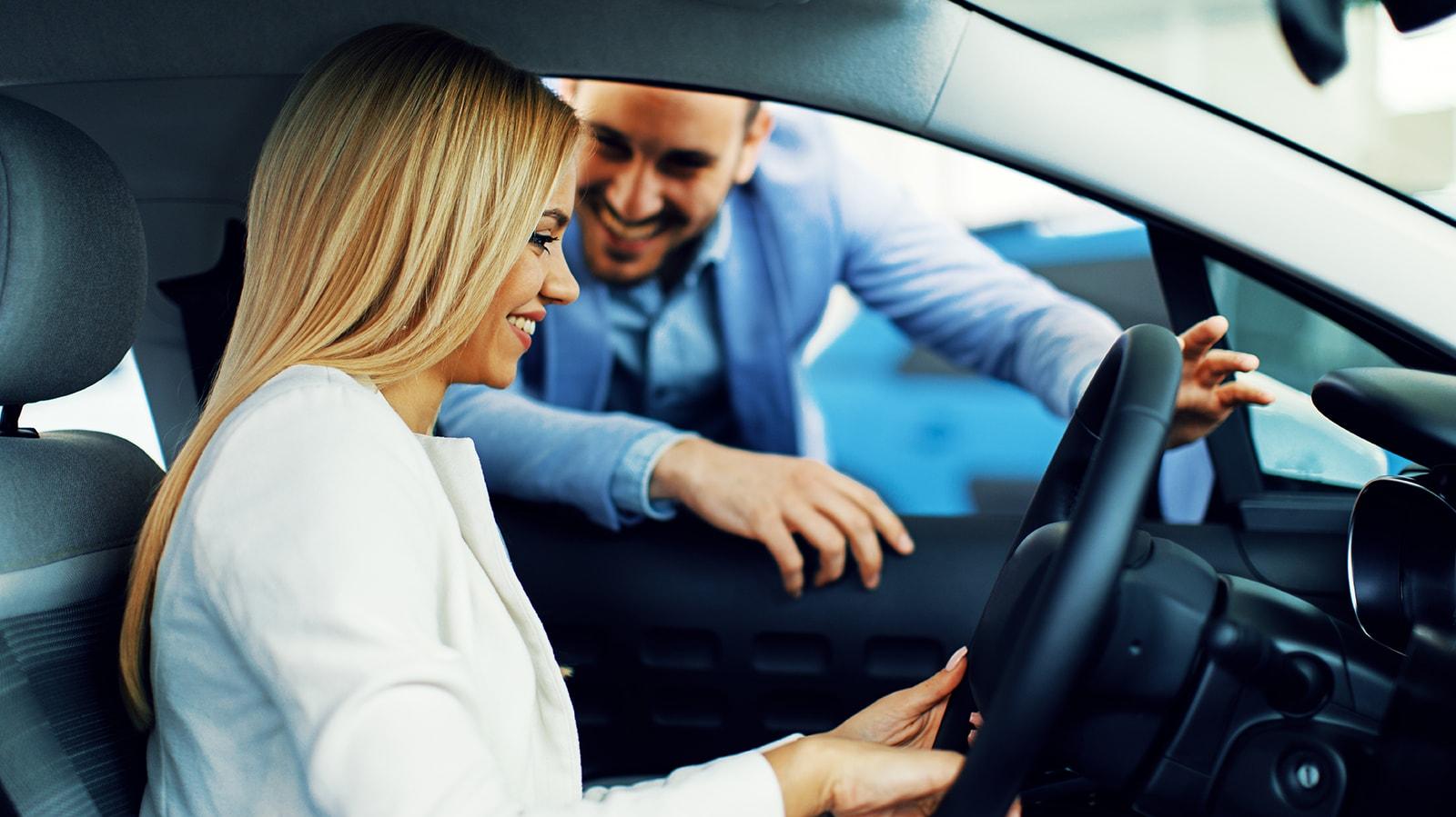 Smiling woman in a dealership sitting in a new vehicle Smiling woman in a dealership sitting in a new vehicle