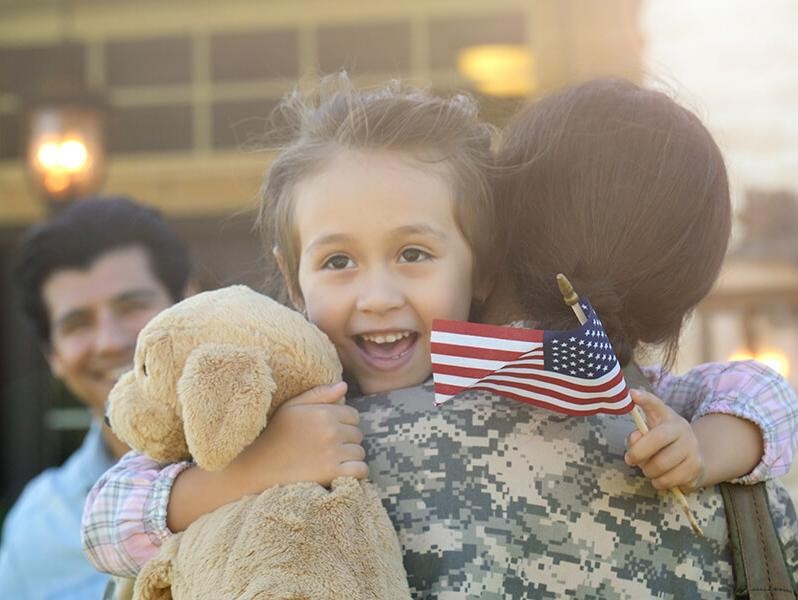 Young girl embracing her military mother