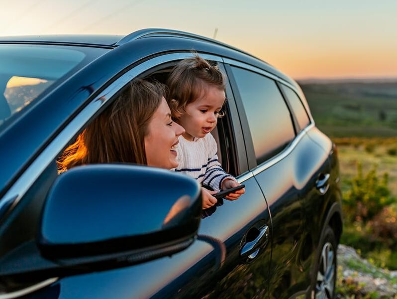 Mother with her young daughter in a car at sunset
