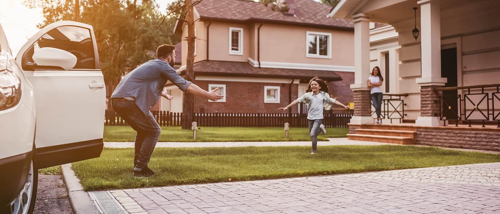 Young girl outside her home running towards her father by their new car